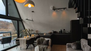 A modern interior with a dining area, a sofa, and a kitchen. - Twin Vista A-Frame Cabins (Sovata)