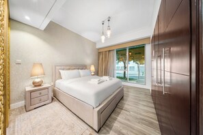 Ein modernes Schlafzimmer mit einem großen Bett, Nachttischlampen, einem Kleiderschrank und Blick ins Freie.