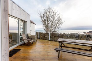 A wooden deck with a stone wall and a view of the sea. - The Deck House | St Monans (St Monans)