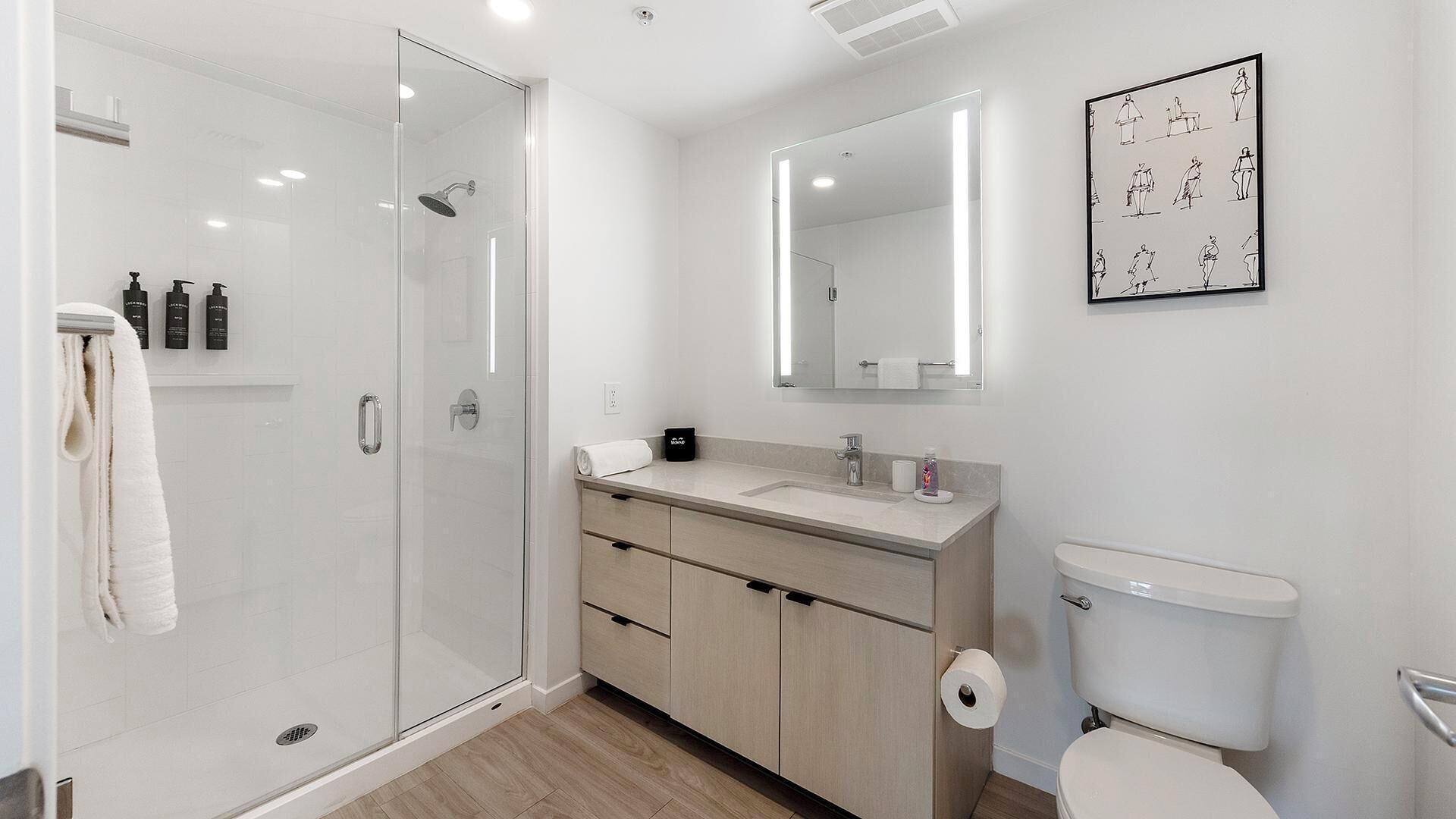 A modern bathroom with a glass shower enclosure, a sink with a mirror above, and a toilet.