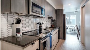 A modern kitchen with a hexagonal tile backsplash, stainless steel appliances, and a view to a dining area. - Landing | Beautiful Studio, Clubhouse, Yoga Studio (Tempe)