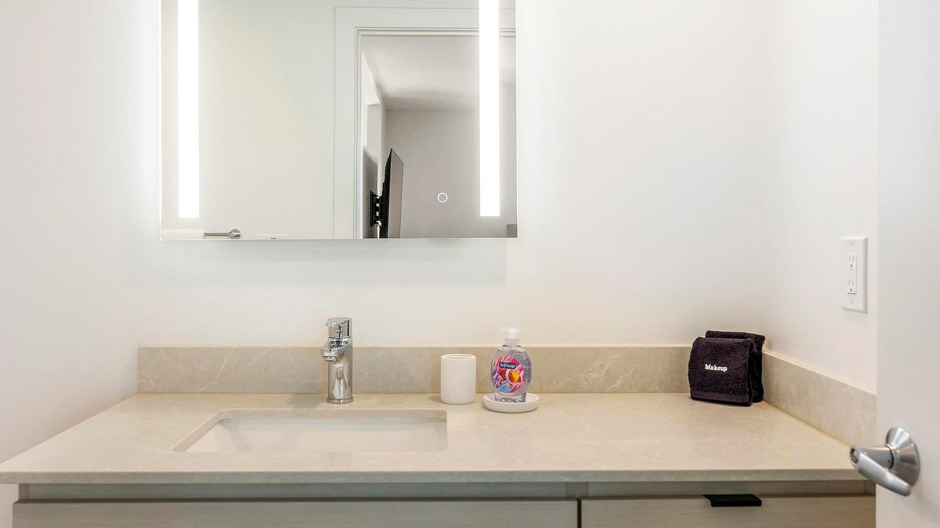 Un baño con lavabo, espejo y artículos de aseo.