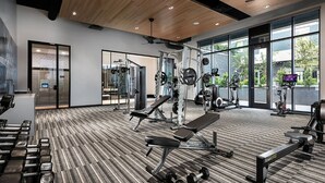 A modern gym with various exercise equipment, large windows, and a wooden floor. - Landing | Beautiful Studio, Clubhouse, Yoga Studio (Tempe)