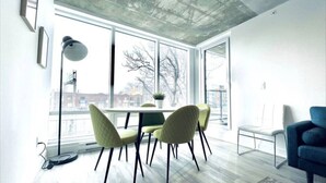 A modern interior with a dining area, large windows, and a view of the outside. - Romema *201* - Condo Luxe 1 bdr (Montreal)