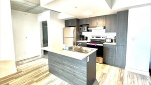 Una cucina moderna con isola centrale, elettrodomestici integrati e soffitto in cemento.