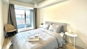 Una camera da letto moderna con un letto grande, un comodino, una sedia e una finestra con tende.