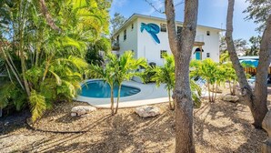 A pool surrounded by palm trees and a building with a blue turtle sculpture. - Beechwood  Suites  D (Sarasota)