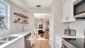 A modern kitchen with white cabinetry, a wooden countertop, and a built-in microwave. - Beechwood  Suites  D (Sarasota)