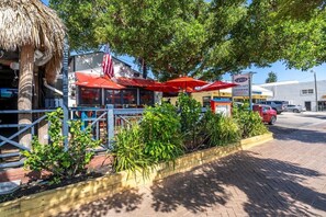 Un restaurante con terraza, techo de paja y una bandera estadounidense.