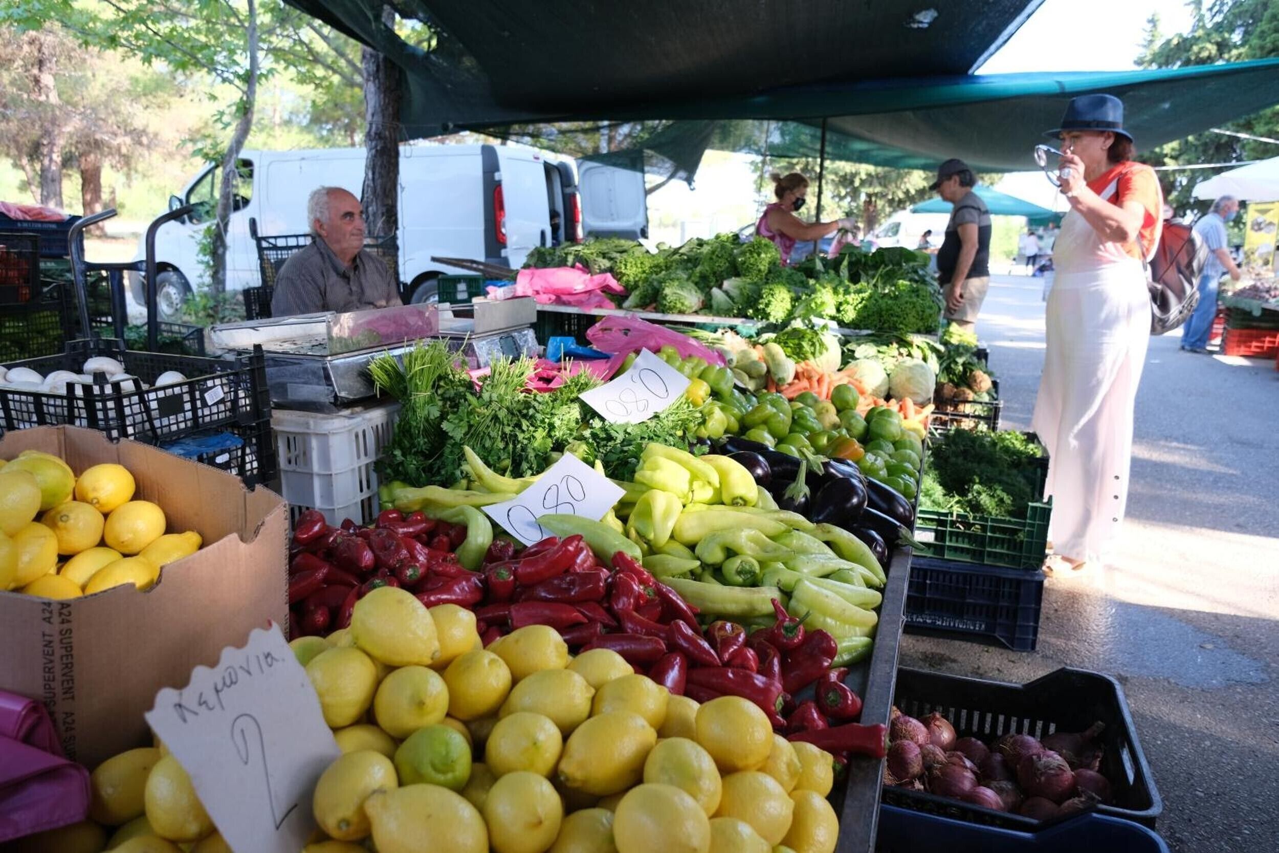 A market stall with various fresh produce like lemons, red peppers, and green beans.