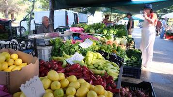 A market stall with various fresh produce like lemons, red peppers, and green beans.