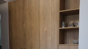 Un armario de madera con un estante superior, un florero con flores secas y un piso de baldosas.