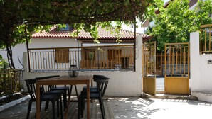 Un patio con una mesa y sillas, un portón y un edificio con tejado de tejas.
