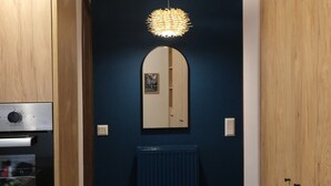 Un pasillo con un armario de madera, horno empotrado, pared azul, espejo y radiador.