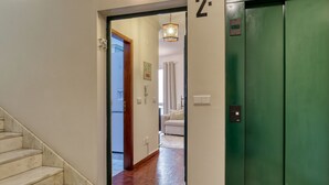 A hallway with a marble staircase, a green elevator, and a door marked with the number 2. - Elvira's Corner, a Home in Madeira (Funchal)