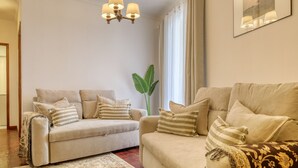A living room with two sofas, a chandelier, a large plant, and a framed picture on the wall. - Elvira's Corner, a Home in Madeira (Funchal)