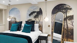 Ein Schlafzimmer mit einem Bett, Kissen, einem Nachttisch, einem Spiegel und einer Wandmalerei.