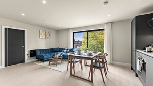 Eine moderne Wohnung mit Essbereich, einem blauen Sofa und einem großen Fenster mit Blick.