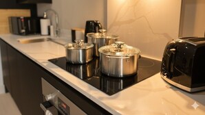 Eine moderne Küche mit schwarzem Arbeitsplatz, Edelstahlkochgeschirr, einem Toaster und einer digitalen Uhr.