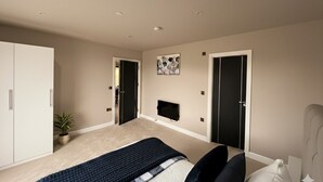 Ein Schlafzimmer mit einem Bett, einem an der Wand montierten Fernseher, einem Kleiderschrank und einer Tür zu einem anderen Raum.