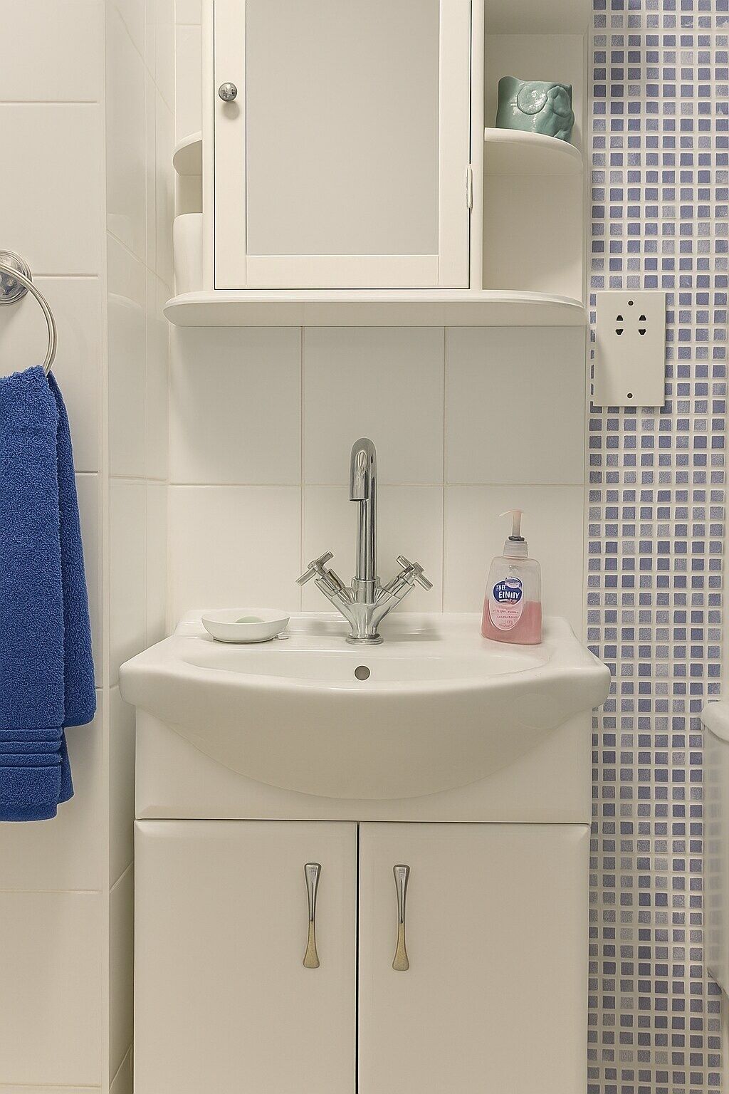 Ein Badezimmer mit einem weißen Waschbecken, einem blauen Handtuch und einer Seifenspender.