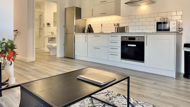 Eine moderne Küche mit weißen Schränken, einem eingebauten Backofen und einer Mikrowelle.