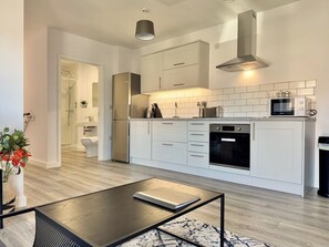 A modern kitchen with white cabinets, a built-in oven, and a microwave. - Boutique Abode in York with Parking (York)