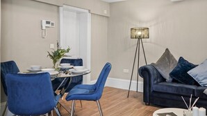 Een moderne woonkamer met eethoek, met een bank, stoelen, een vloerlamp en een eettafel met stoelen.