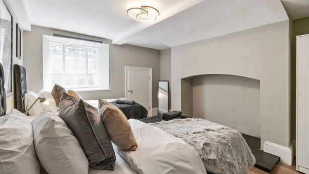 Een slaapkamer met een bed, een raam, een deur en een plafondlamp.
