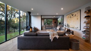 Ein modernes Wohnzimmer mit einem großen grauen Ecksofa, einem Kamin und Blick ins Freie.