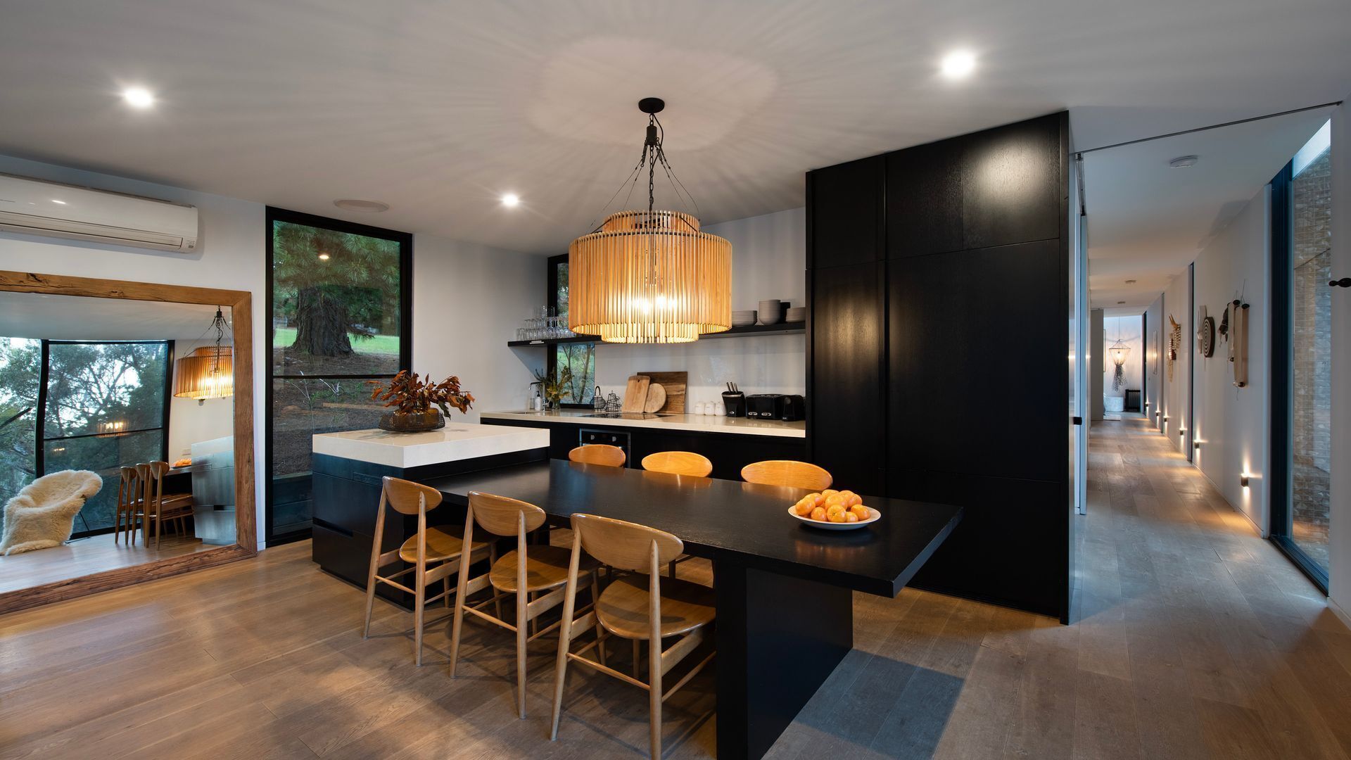 Une cuisine moderne avec un îlot central, des chaises en bois et un luminaire suspendu.