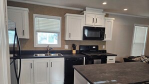 A modern kitchen with white cabinets, a black microwave, and a stainless steel refrigerator. - Lakefront retreat on West Battle Lake cozy, modern, and steps from the water! (Battle Lake)