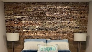 A bed with a striped bedspread, two bedside lamps, and a decorative pillow with text. - Lakefront retreat on West Battle Lake cozy, modern, and steps from the water! (Battle Lake)