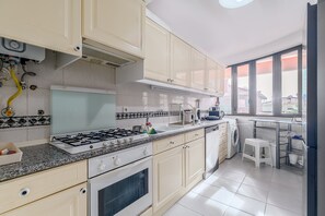 A kitchen with a gas stove, oven, sink, and a washing machine. - Apartment 'Casa De Stefan' with Balcony (Cascais)