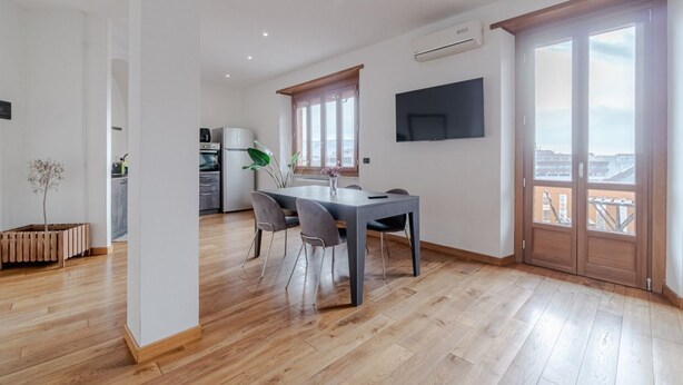A modern living space with a dining area, a kitchen, and a large window with a view. - GuestHost - Spacious and bright apartment of approximately 80 square meters, perfect for four people, located on the fifth floor of a building (NO elevator).The property is located in a quiet area and well-connected to the center of Turin by surface tran (Turin)