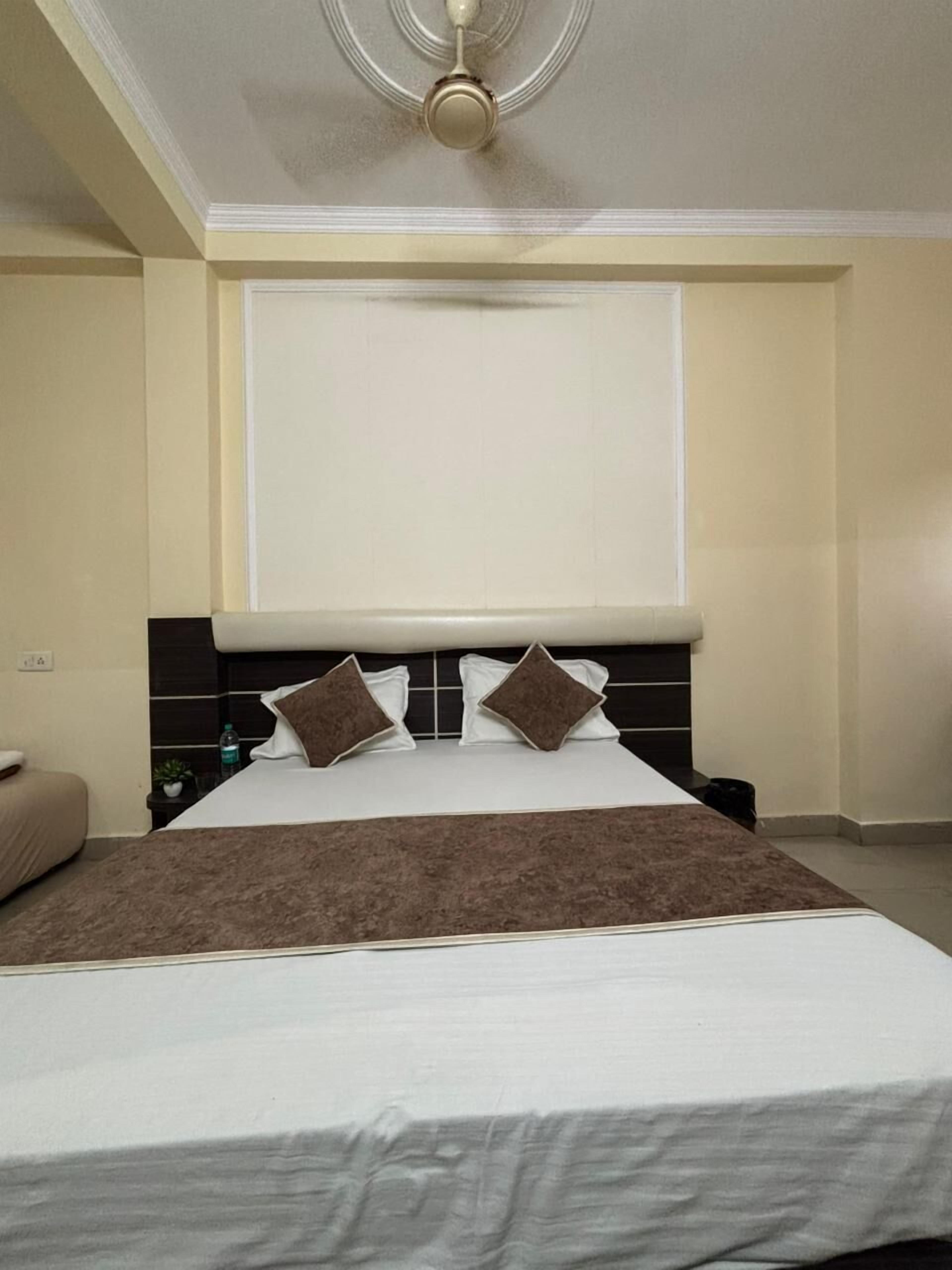 A hotel room with a large bed, a headboard, and a ceiling fan.
