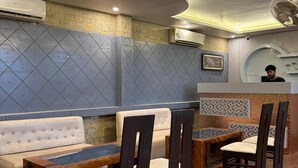 A restaurant interior with a long counter, cushioned seating, and a decorative wall.