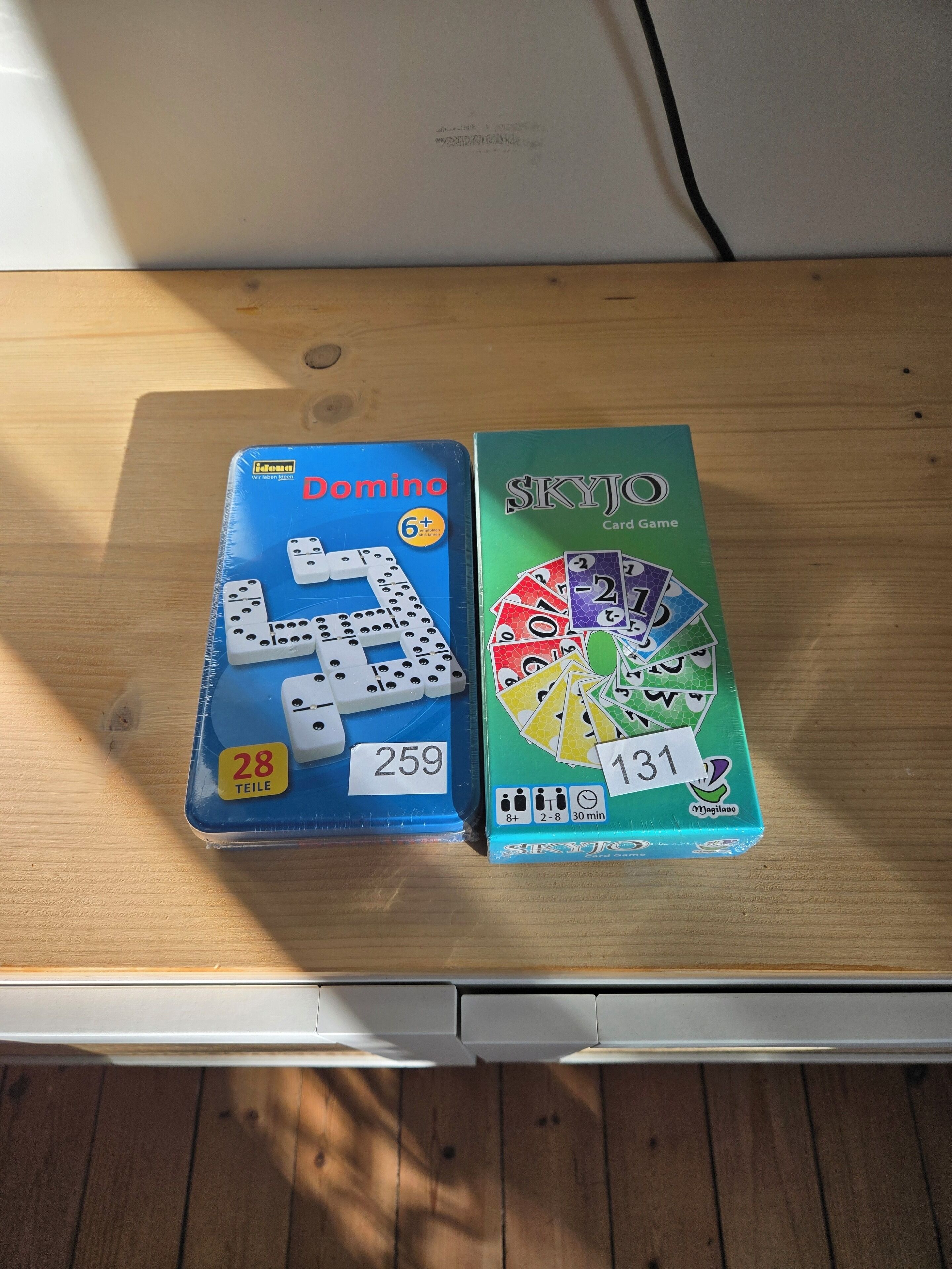 Zwei Brettspiele, Domino und Skyjo, auf einem Holztisch.