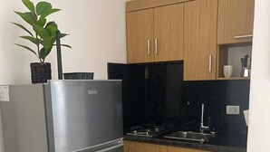 Une cuisine avec des meubles en bois, un réfrigérateur en acier inoxydable, un évier et une plante en pot.