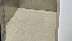 Un ascenseur vide, avec des parois métalliques et une barre de maintien.