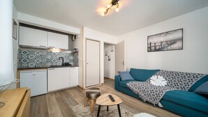Un espacio habitable compacto con kitchenette, un sofá y un cuadro en la pared.