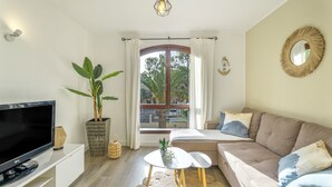 A modern living room with a flat-screen TV, a sofa, a coffee table, and a large window with curtains. - Vacation Apartment 'Tagoropark Relax' with Shared Pool, Private Terrace and Wi-Fi (Costa del Silencio)