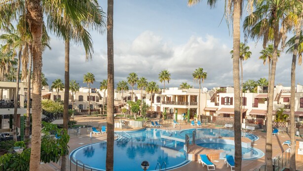 A resort with a central swimming pool, palm trees, and multiple buildings with balconies. - Vacation Apartment 'Tagoropark Relax' with Shared Pool, Private Terrace and Wi-Fi (Costa del Silencio)