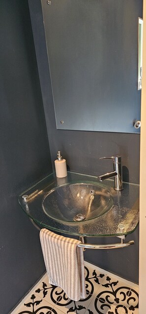 A bathroom with a glass sink, a towel rack, and a mirror. - Onetangi Seaview Residence (Waiheke Island)