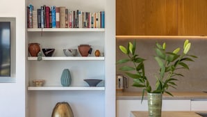 Eine moderne Küche mit Holdekor, einem weißen Regal voller Bücher und einer Vase mit grünen Blättern.