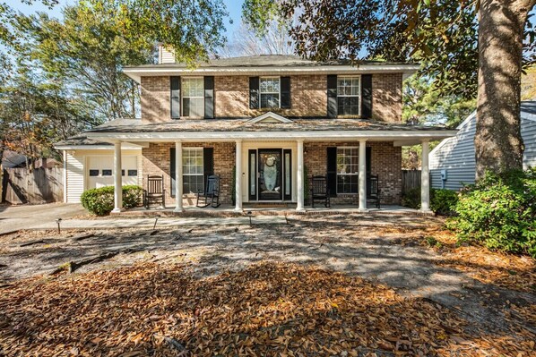 A two-story house with a porch, brick exterior, and a covered front entrance.