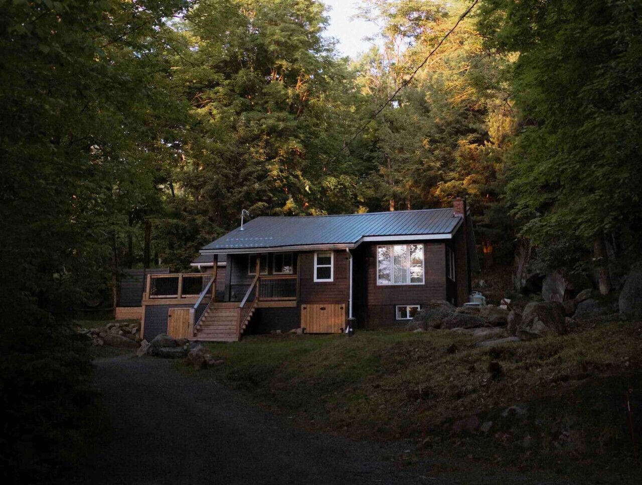 A cabin with a wooden exterior, a metal roof, and a staircase leading to a deck.