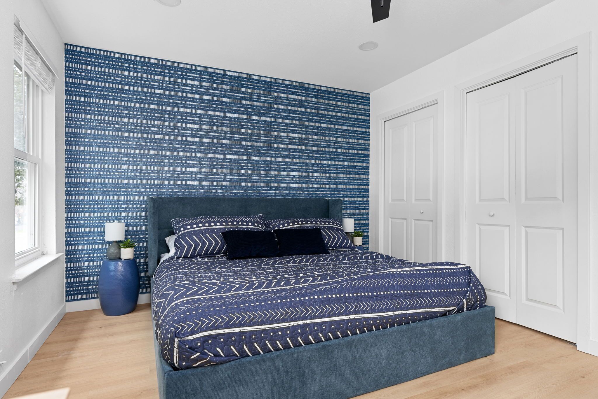 Een slaapkamer met een groot bed, een blauwe behang en een witte deur.