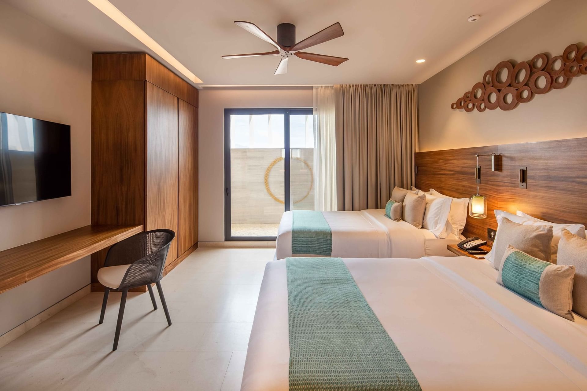 Une chambre d’hôtel équipée d’un lit, d’un bureau, d’une chaise, d’une télévision et d’un ventilateur de plafond.