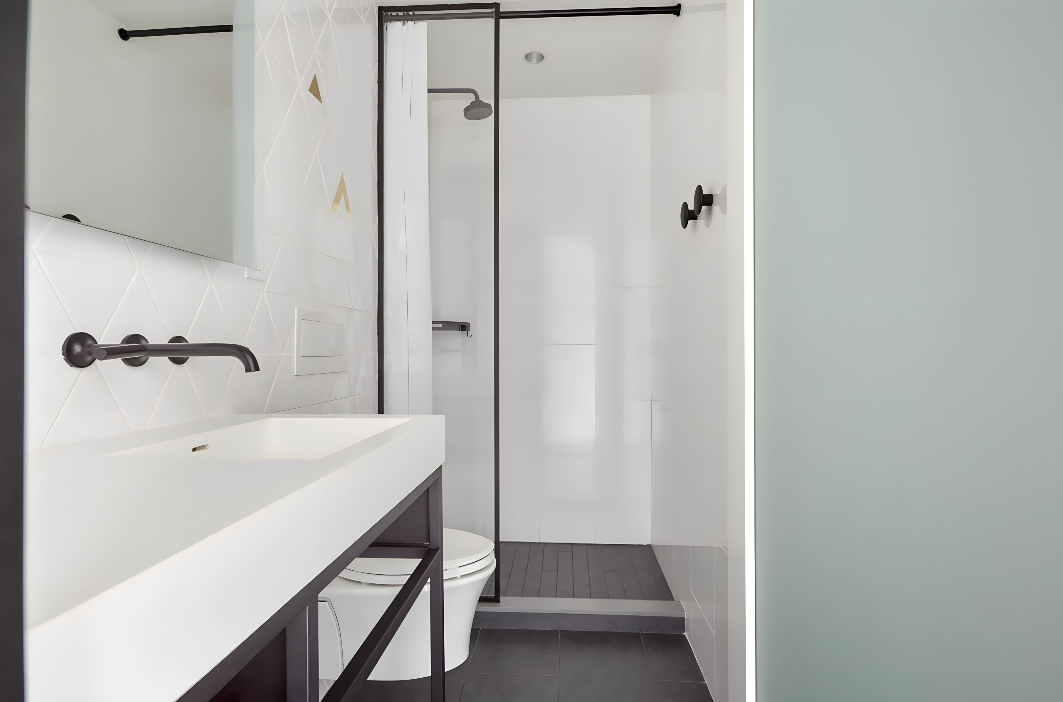 A modern bathroom with a white sink, a glass shower enclosure, and a toilet.